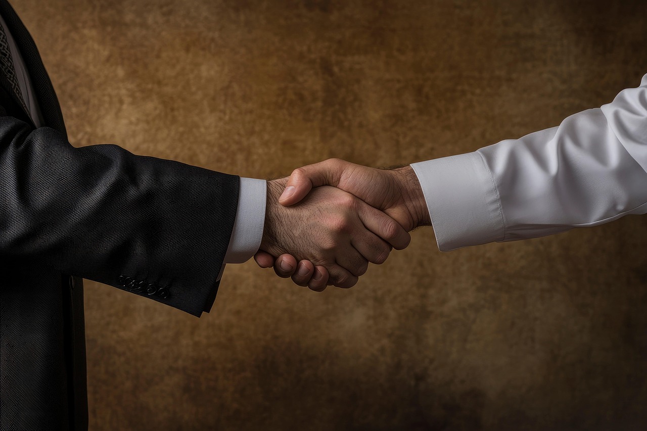 Dos personas dándose la mano en señal de acuerdo con fondo marrón.